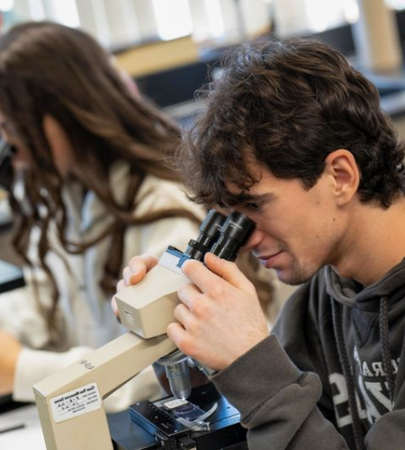 Holy Family University students in a lab looking through microscopes